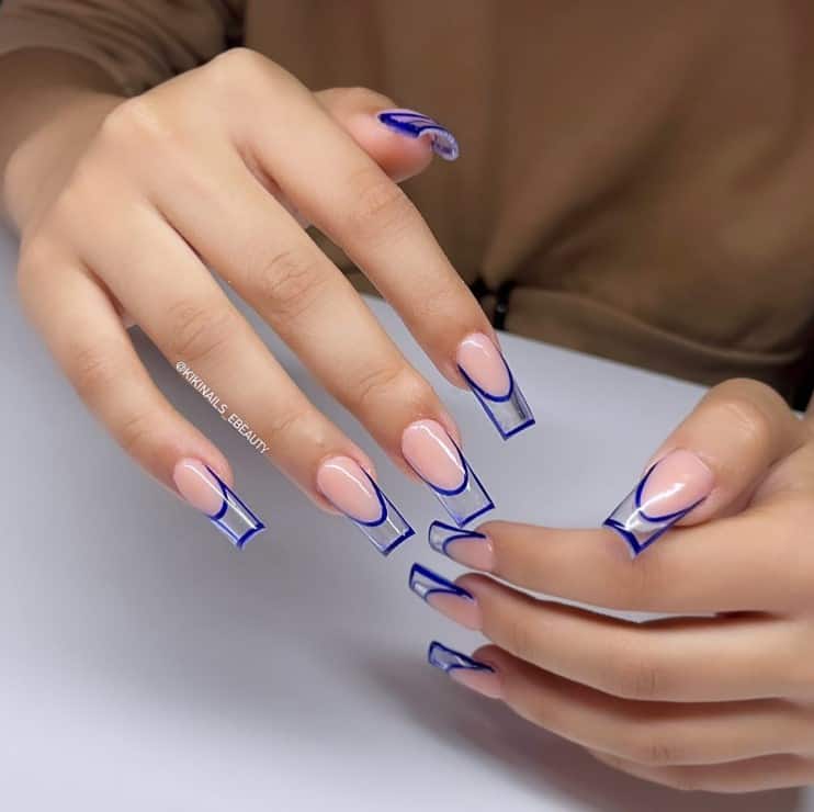 A woman's hands with peach nail polish base that has blue nail polish tips