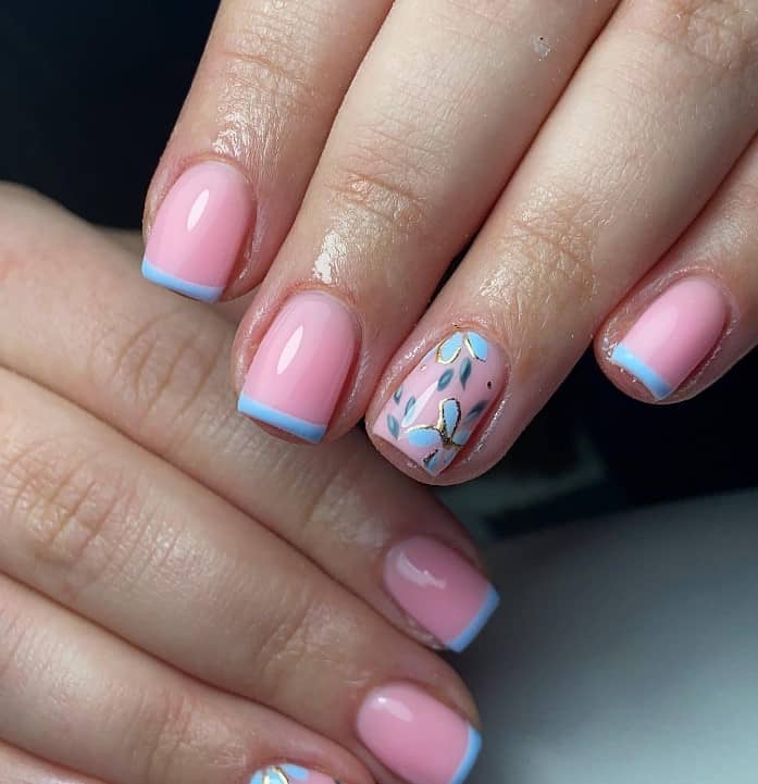 A closeup of a woman's hands with pastel pink nail polish base that has thin line of pastel blue nail tips and leaves and florals nail designs