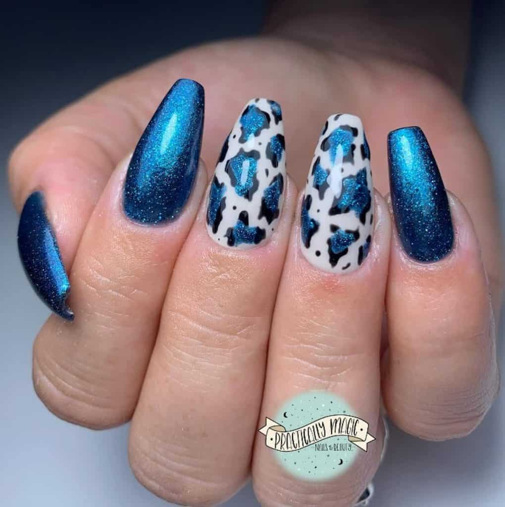 A closeup of a woman's hand with shimmery denim blue polish that has an animal print nail design