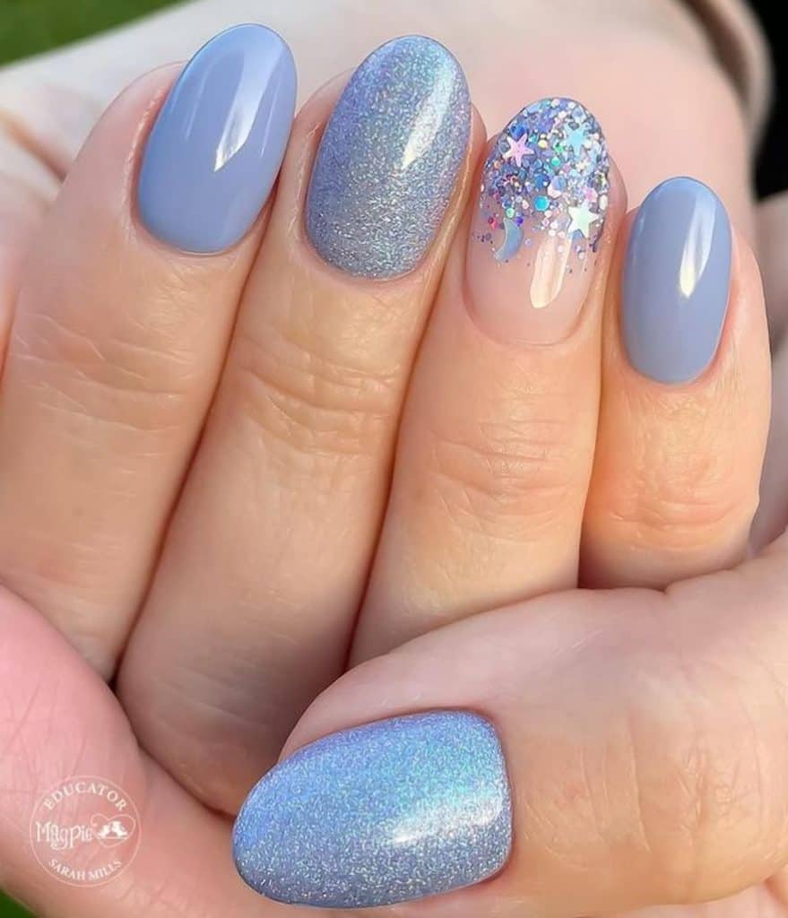 A closeup of a woman's hand with blue gel nails that has glitter and holographic glitter confetti nail designs on select nails