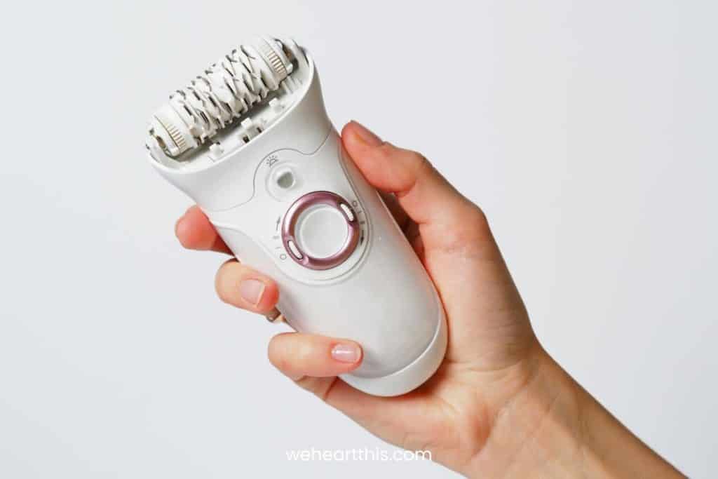 Female epilator white in a female hand on a white background. Electric hair removal device. 