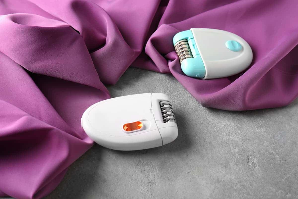 Two pieces of epilator on a purple fabric on top of a gray surface