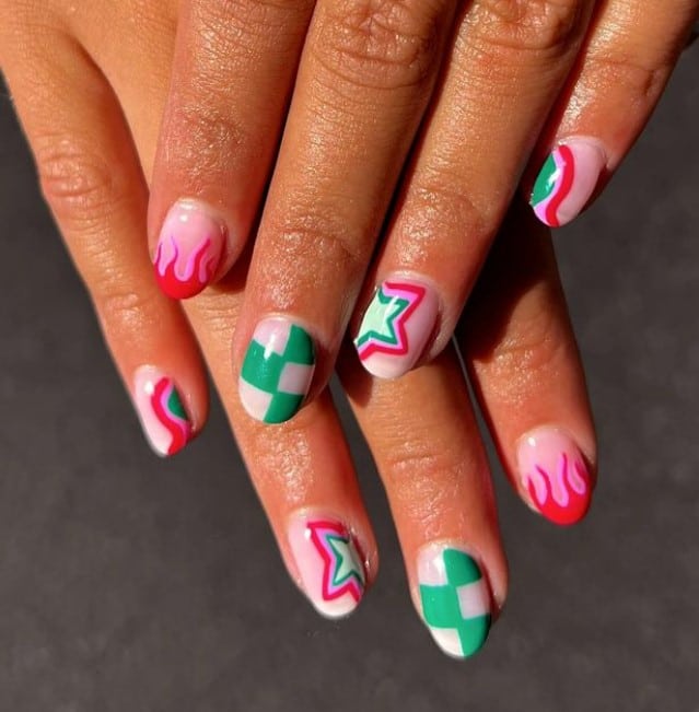A closeup of a woman's hands with off white nail polish base that has checkboard patterns, retro beaming stars, and hot pink flames nail art