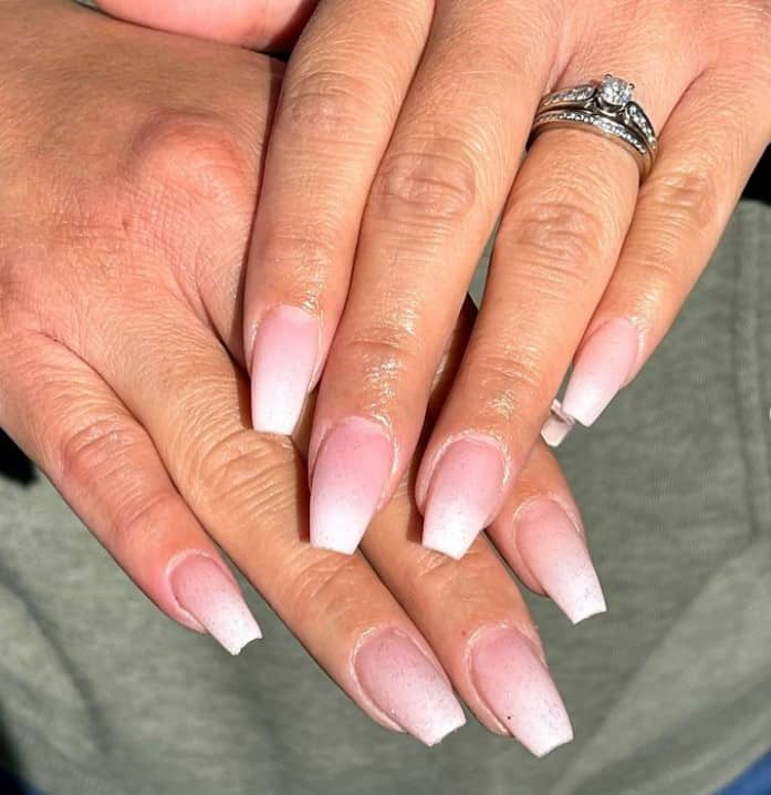 A woman's hands with pale pink nail polish that has white nail tips 
