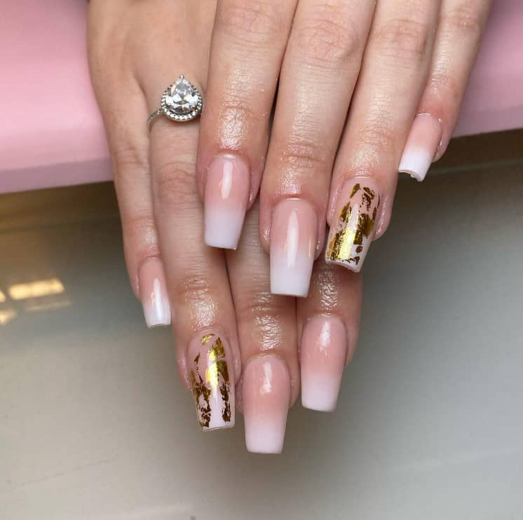 A woman's hands with pale pink nail polish and white nail tips that has gold glitter nail designs
