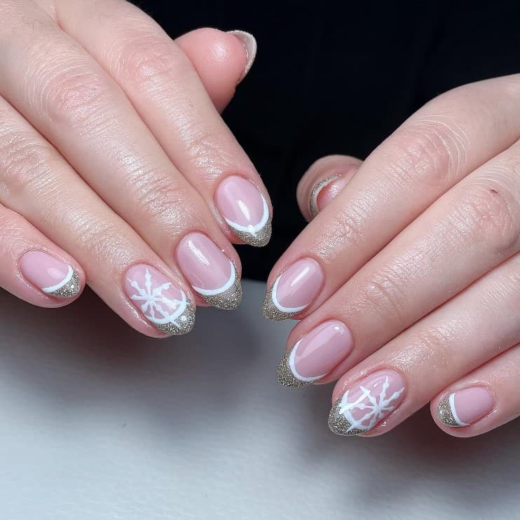 A closeup of a woman's hands with nude nail polish that has classic French manicure with its pink, white tip outlines, and glittery gold tips combination