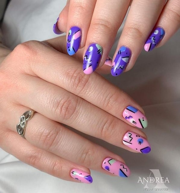A woman's fingernails with light pink and purple nail polish that has geometric doodles in blues, purple, pink, and white