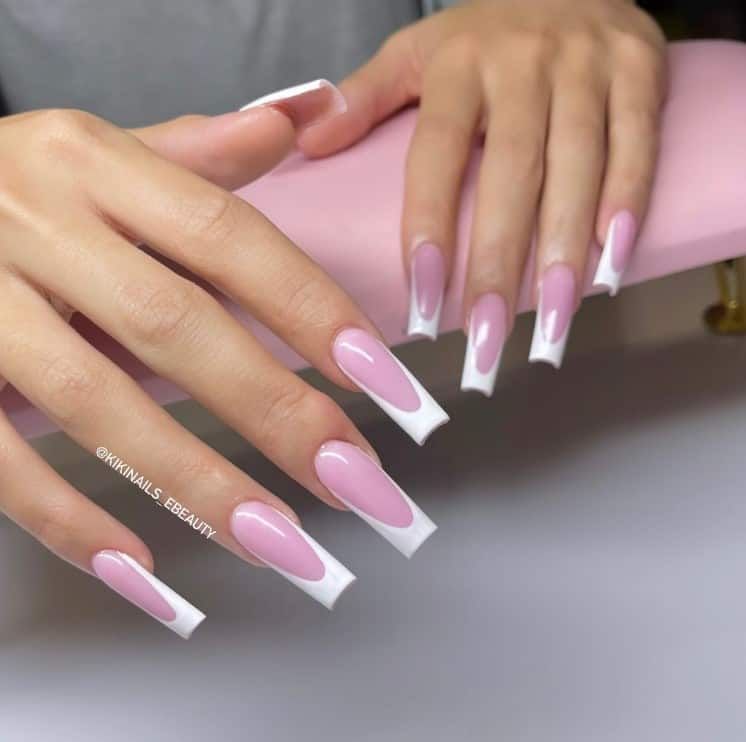 A closeup of a woman's hands with baby pink nail polish base that has white French tips 