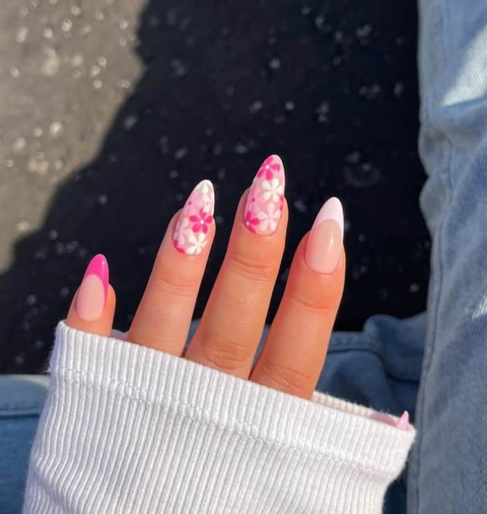 A woman's hand with a nude nail polish that has pink and white French tips and pink-and-white flowers
