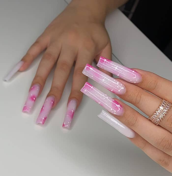 A closeup of a woman's hands with pink and pearly white acrylic nail polish that has 