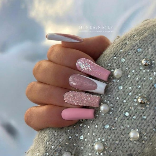 A woman's hand with a soft pink nail polish that has sugary glitter powder and white French tip