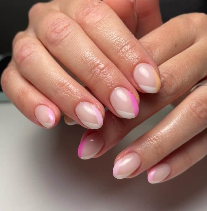A closeup of a woman's hands with nude nail polish base that has delicate colors of white and different shades of pink in v-tips