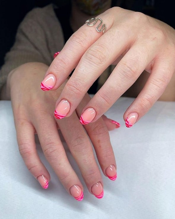 A woman's hands with pastel pink nail polish that has hot pink zebra stripes 