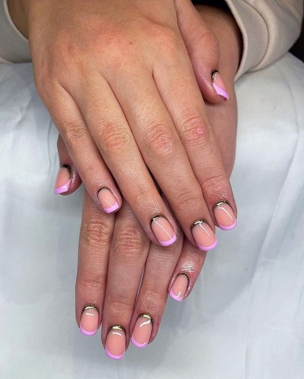 A closeup of a woman's hands with pale pink nail polish base that has pink nail tips 