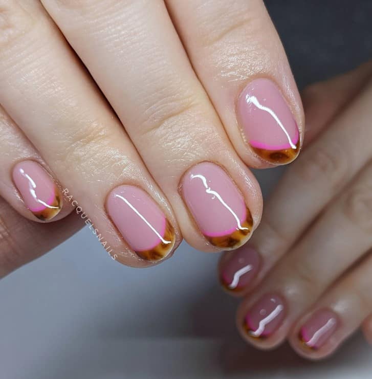 A closeup of a woman's hand with pale pink nail polish that has tortoiseshell French tips with a neon pink outline