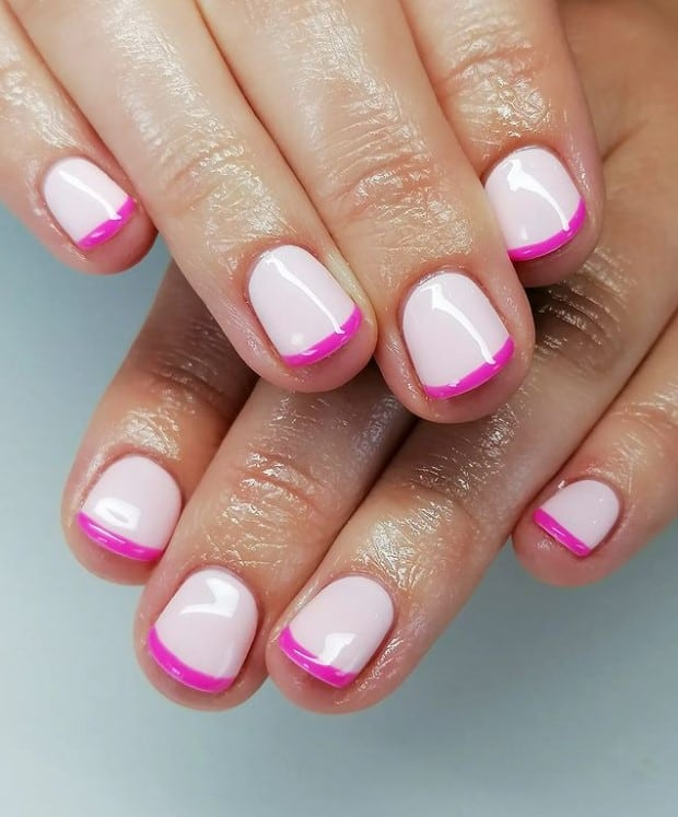 A closeup of a woman's hands with milky white nail polish base that has thin pink tips