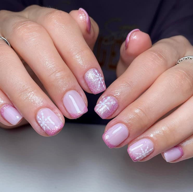 A closeup of a woman's hands with light purple nail polish base that has luxurious glittery pink polish and glittery pink tips and cuffs