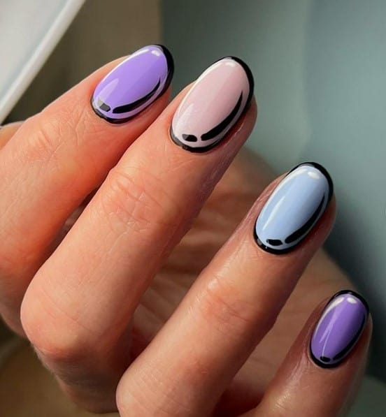 A closeup of a woman's fingernail with pastel nail polish that has black outlines and white highlights