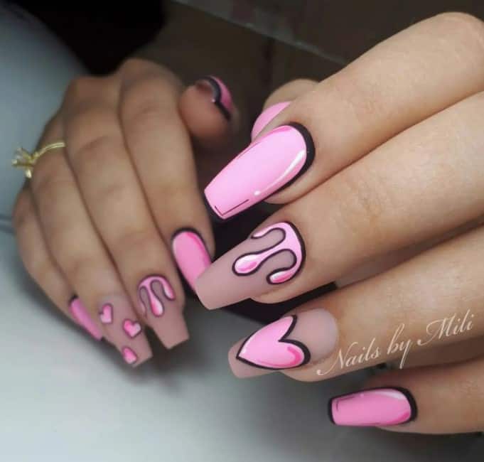 A closeup of a woman's mid-length coffin-shaped fingernails with nude nail polish that has drip nail art and cute pop art hearts