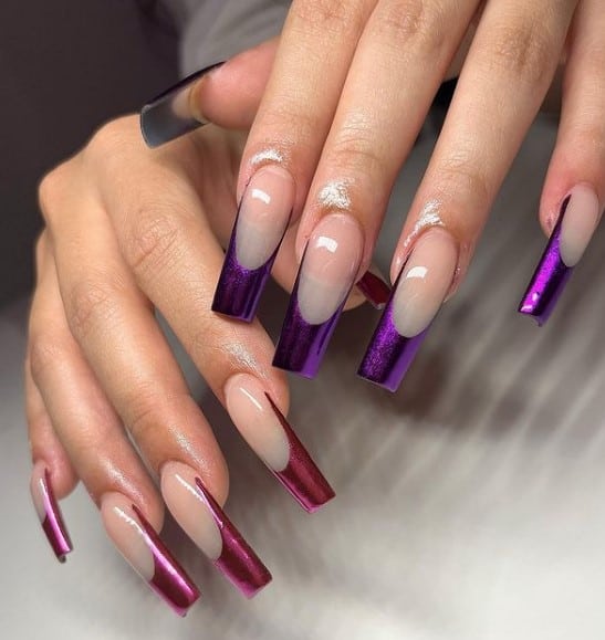 A closeup of woman's fingernails with nude nail polish base that has deep purple and wine-red chrome tips