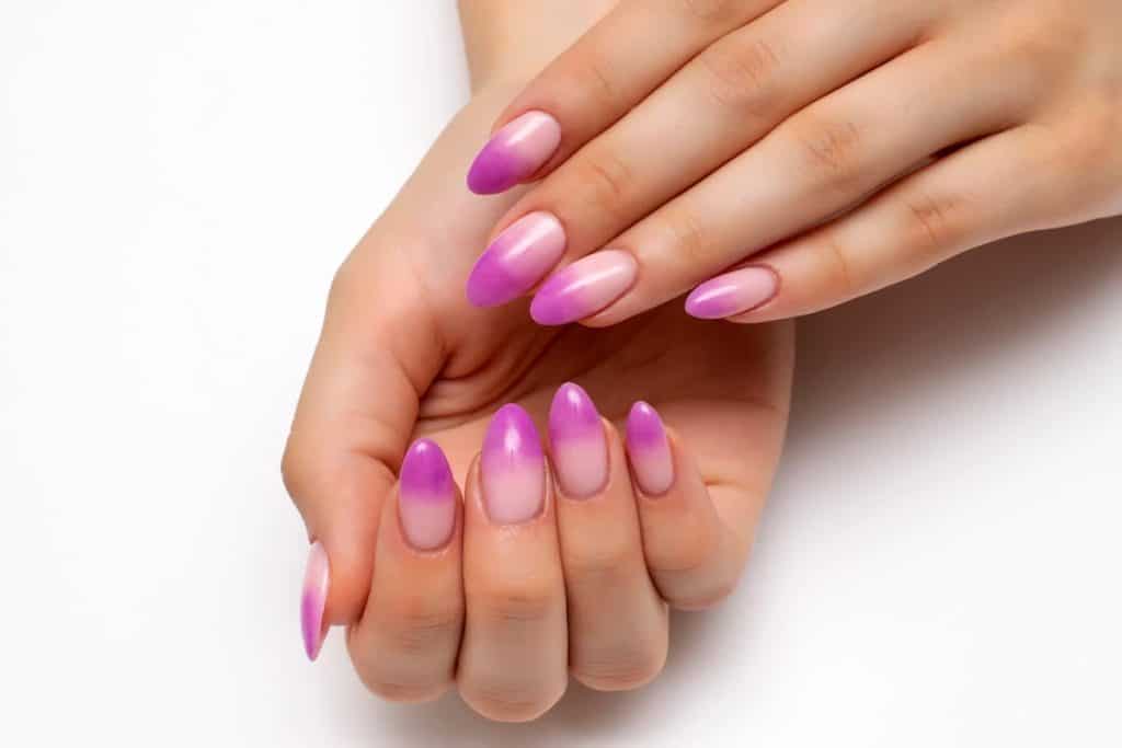 A woman's beautiful almond nails with a purple orchid ombré nail polish