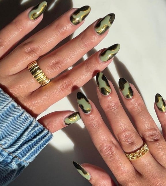 A woman's fingernails with a sage green gel nail polish that has a combination of sage green, black, and gold to mimic animal print