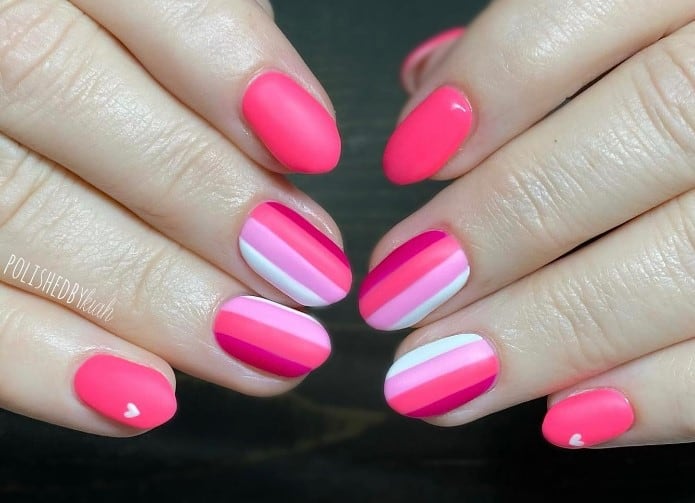close up photo of woman's fingernails with vertical stripes designs colored with pink nail polish