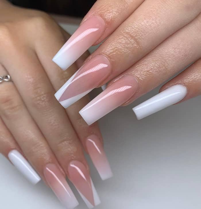 A closeup of a woman's fingernails with a white and nude ombré nails that has white V-tips