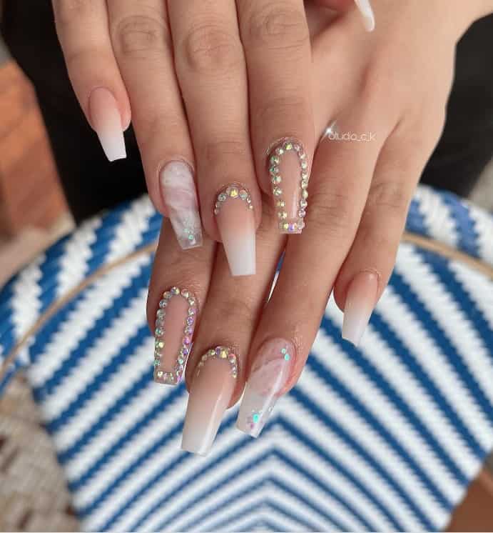 A woman's fingernails with beige ombré nails that are are paired with marble nails and nude nails