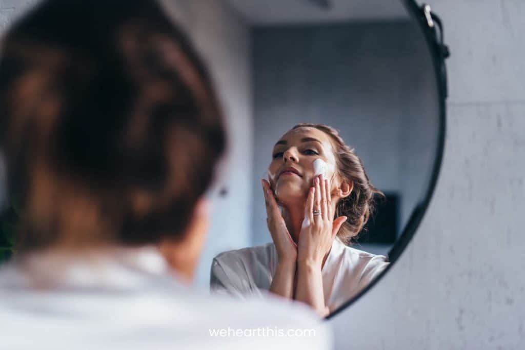 A woman using a face wash for hyperpigmentation while looking at herself in the mirror