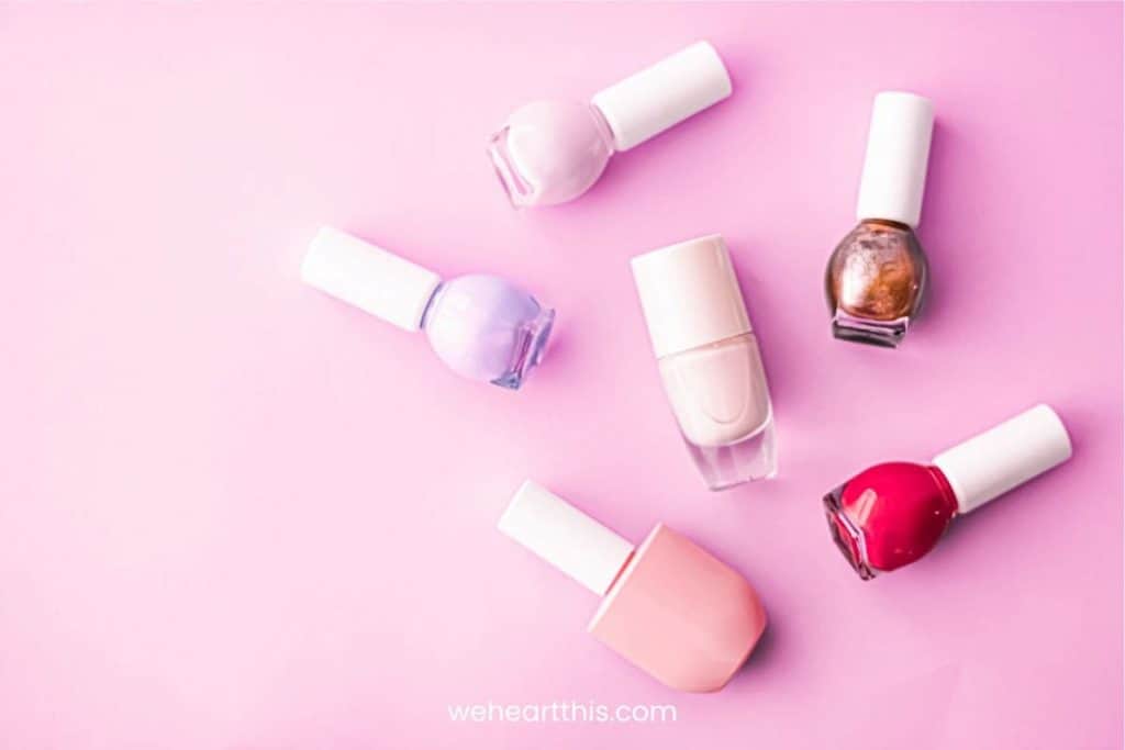 Multicolored nail polish bottles on a pink background