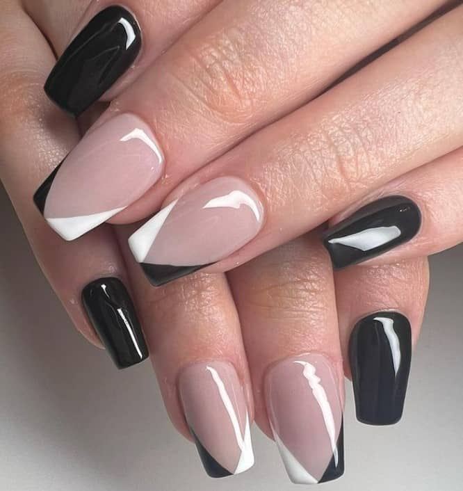 A closeup of a woman's coffin fingernails with a combination of a glossy nude and black nail polish that has V-shaped black-and-white French tips