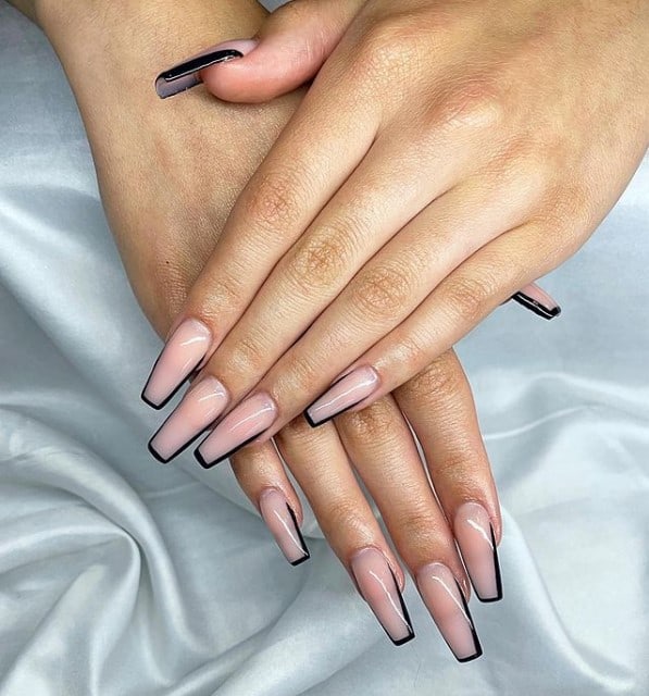A woman's fingernails with a nude nail polish base that has ultra-thin black French tips