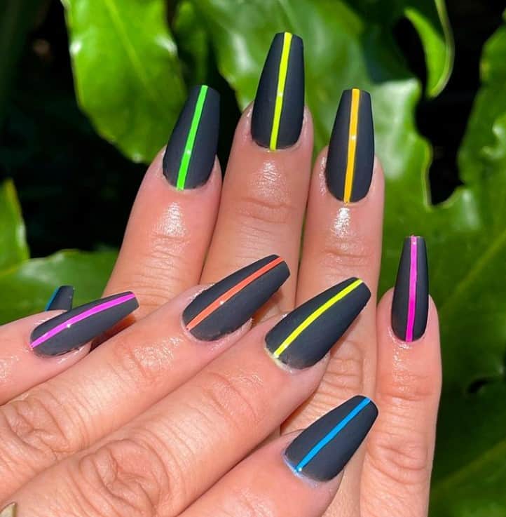 A closeup of a woman's coffin fingernails with black nail polish that has a thin line in the middle of each nail in multiple neon colors