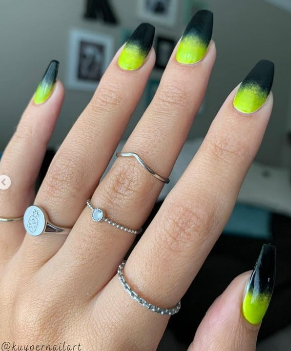A closeup of a woman's fingernails with neon yellow-green to black ombré manicure 