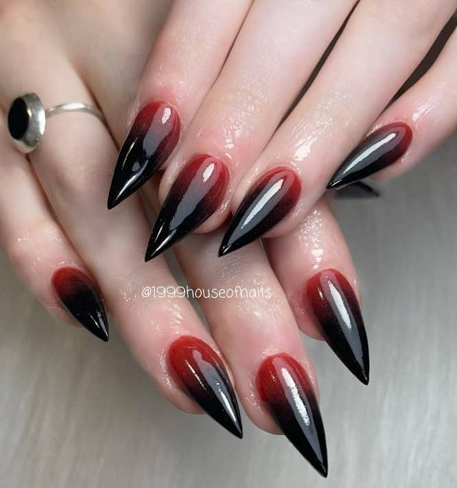 A closeup of a woman's stiletto fingernails with red-and-black ombré that has top coat with a gorgeous glossy finish