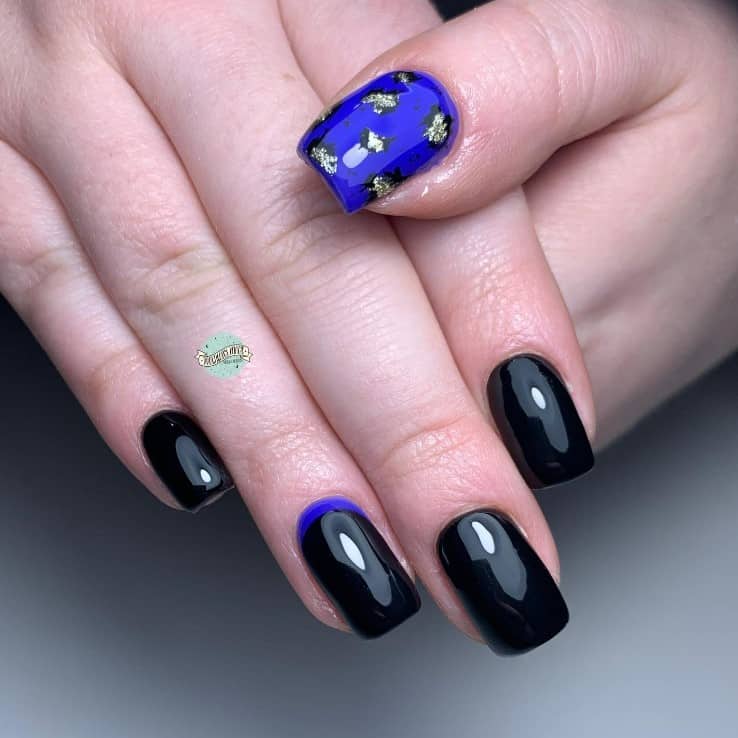 A closeup of a woman's black square fingernails with a regal curved line in royal blue that has leopard prints created using silver flecks outlined in black