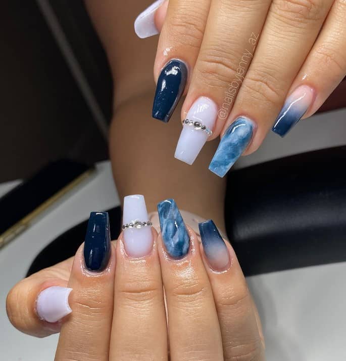 A woman's fingernails with solid nail colors that has jeweled nails or marble art
