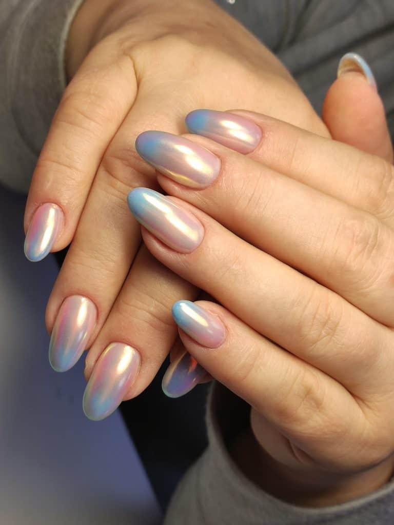 A closeup of a woman's fingernails with a blue-and-nude ombré nail polish that has a pearlescent finish