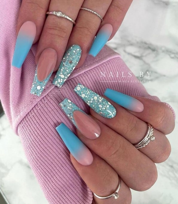 A woman's fingernails with pink-and-blue ombré nail polish that has tiffany blue glitter nails and French tips