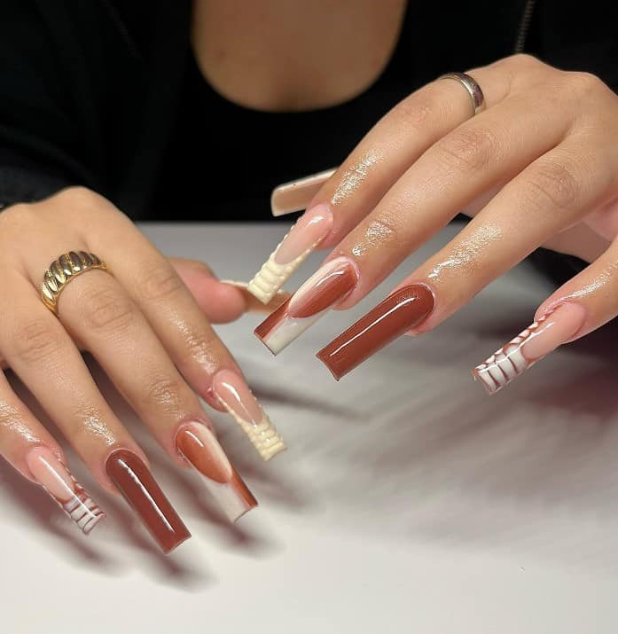 A woman's fingernails with a combination of caramel brown nail and nude nail polish that has brown-and-white gradient over white French tips, painted croc print tips in brown, and 3D croc print tips in white