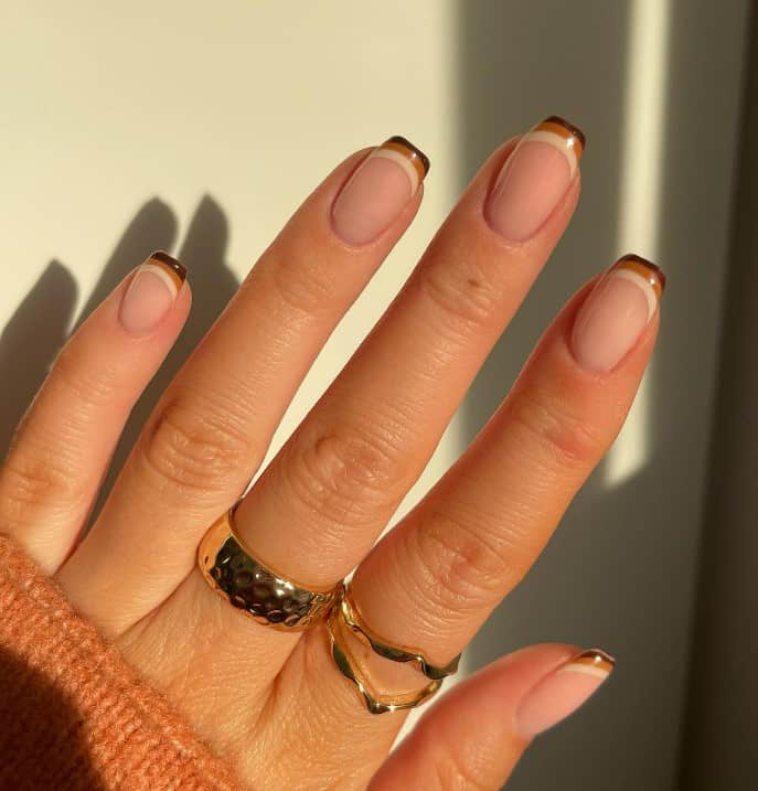 A woman's fingernails with a nude nail polish that has deep brown, caramel, and beige on each nail tip 