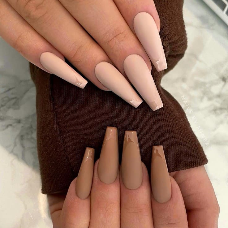 A closeup of a woman's fingernails with a lighter shade of brown for the nails on one hand and a darker shade of brown for the nails on the other