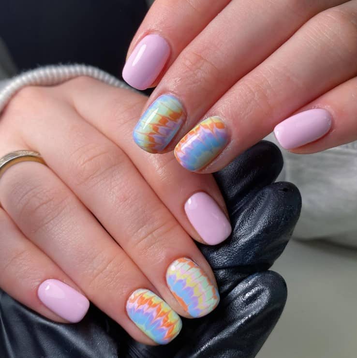 A closeup of a woman's fingernails with a pastel and tie-dye patterns nail polish 