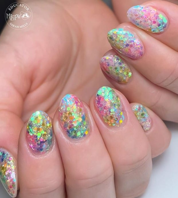 A closeup of a woman's fingernails with a chunky glitter nail polish 