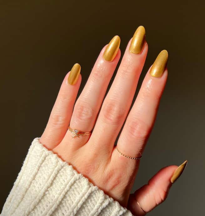 A woman's fingernails with a citrine nail polish that has a subtle sparkly finish