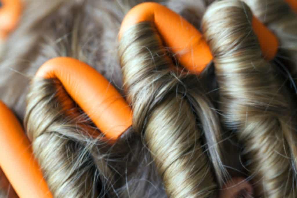 A close up of a woman's hair with orange flexi rods on it