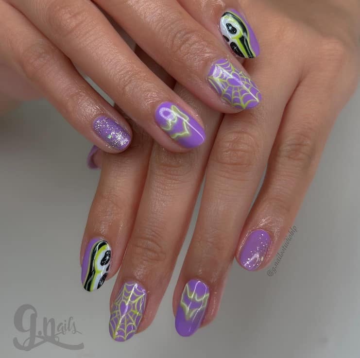 A closeup of a woman's fingernails with a soft lavender nail polish base that has spiderweb, bat, and Ghostface nail designs with a touch of glittery silver