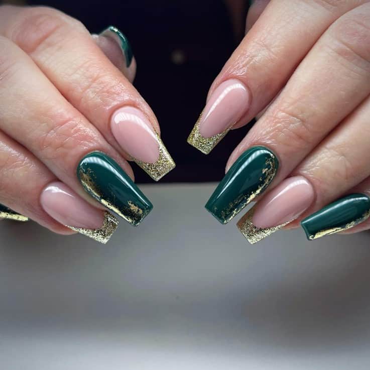 A closeup of a woman's fingernails with a nude and green nail polish base that has gold glitter French tips