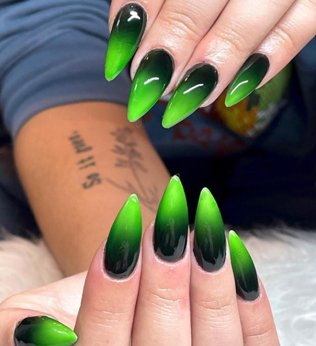 A closeup of a woman's fingernails with a black-and-green ombré nails